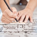 Architect drawing building floor plan, design blueprint map and engineer drafting structure on table paper. Real estate development work office construction and industrial wall safety ruler.